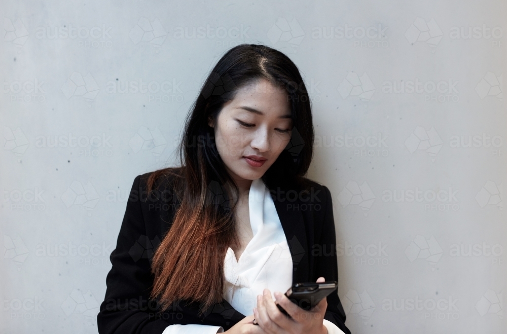 Young Asian businesswoman checking emails on her mobile - Australian Stock Image