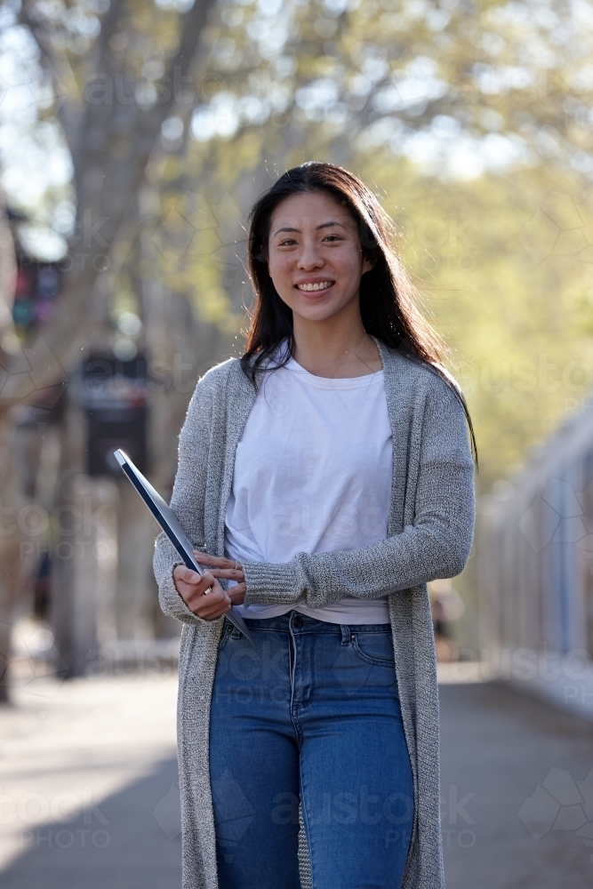 Young Asian female university student carrying study notes - Australian Stock Image