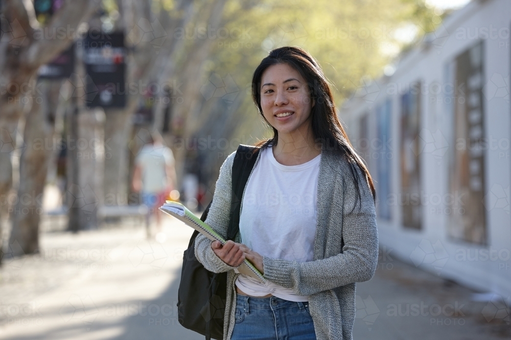 Young Asian female university student carrying study notes - Australian Stock Image