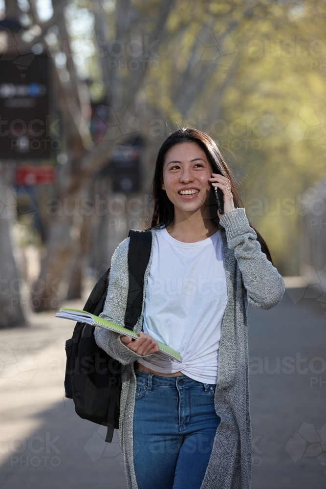 Young Asian female university student on mobile phone - Australian Stock Image