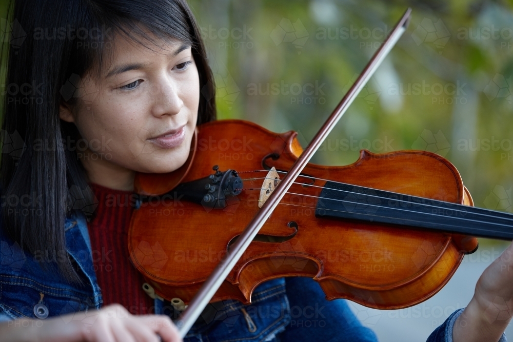 Young Asian female violin player practising outdoors - Australian Stock Image