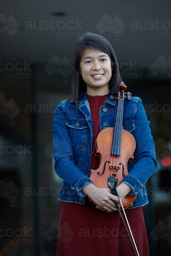 Young Asian female violin player practising outdoors - Australian Stock Image