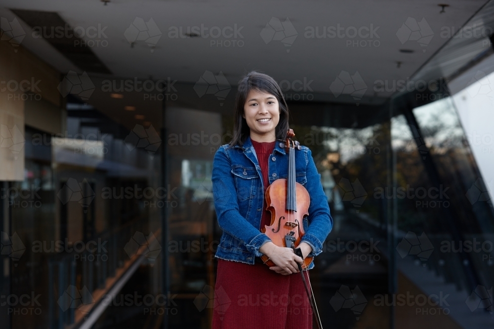 Young Asian female violin player practising outdoors - Australian Stock Image
