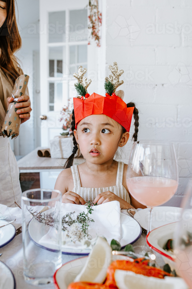 Young Asian girl seated on the table glancing sideways - Australian Stock Image