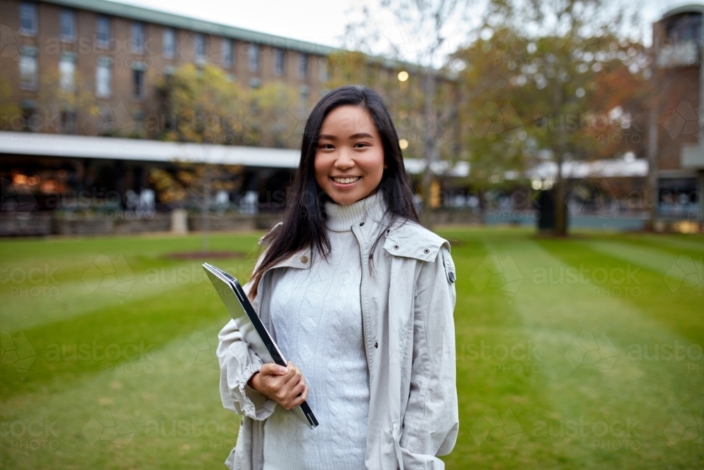 Image of Young Asian student holding her laptop on lawn at university ...