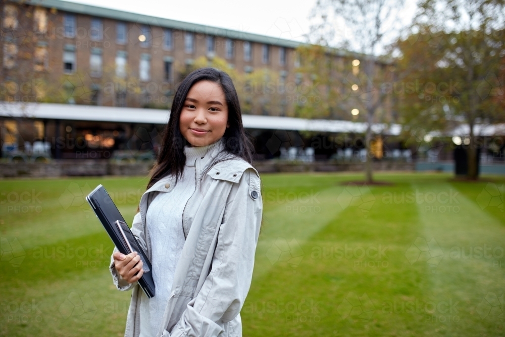 Image of Young Asian student holding her laptop on lawn at university ...