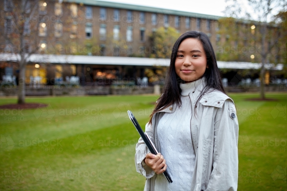 Image of Young Asian student holding her laptop on lawn at university ...