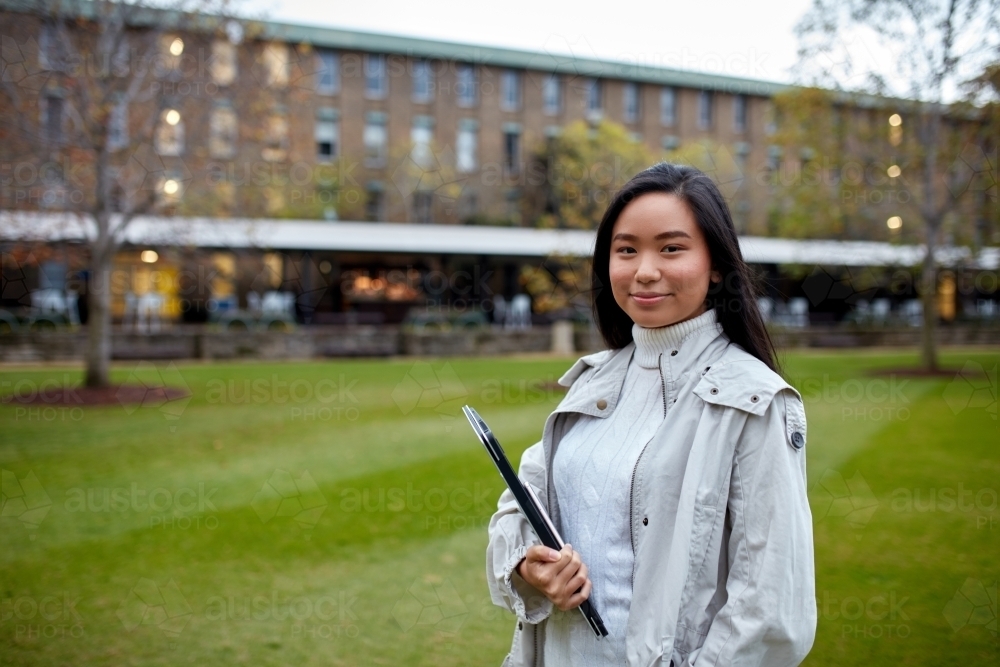 Image of Young Asian student holding her laptop on lawn at university ...