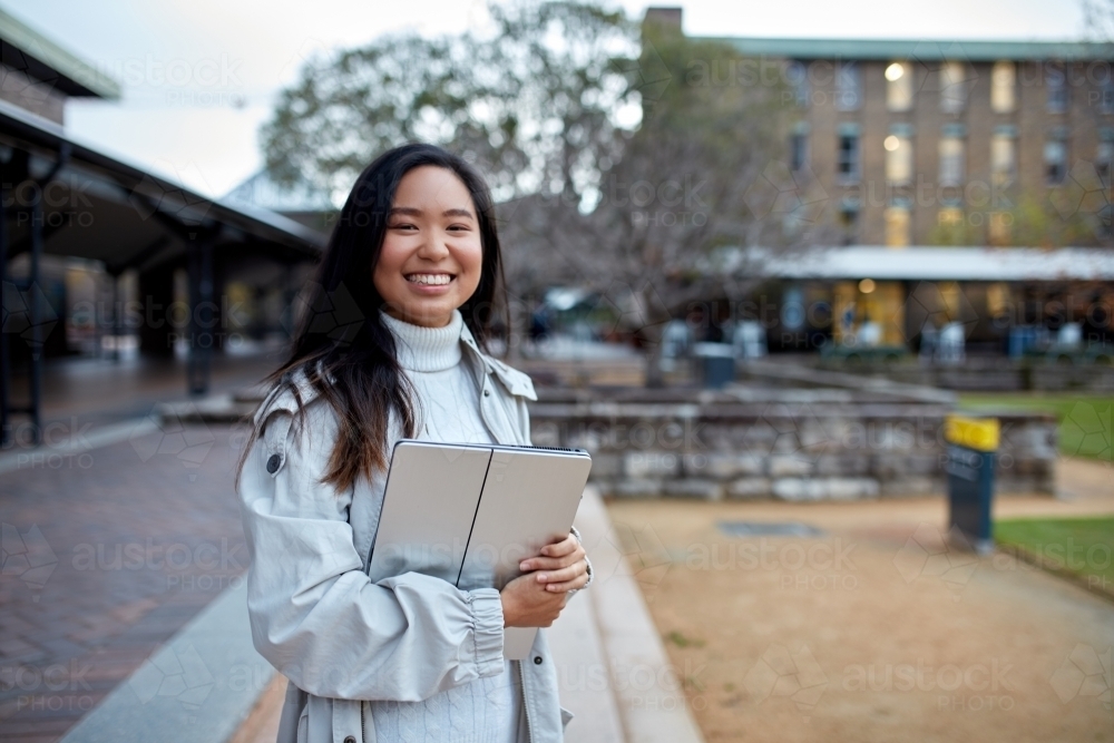 Image of Young Asian student holding her laptop on lawn at university ...