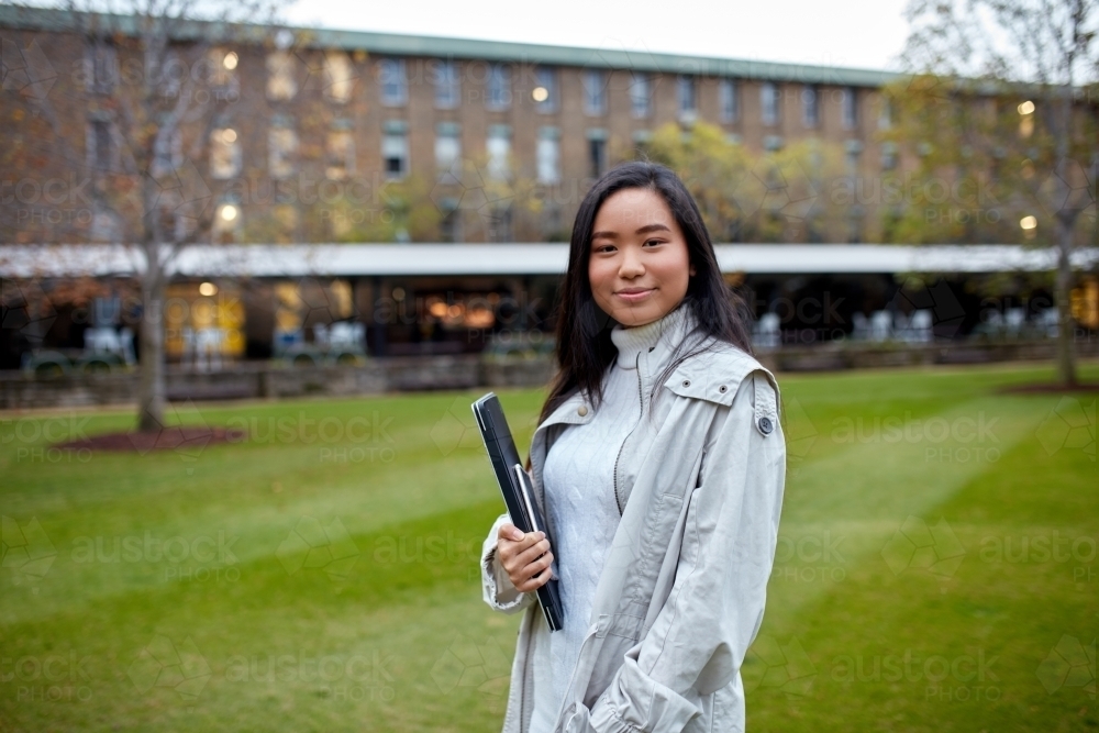 Image of Young Asian student holding her laptop on lawn at university ...
