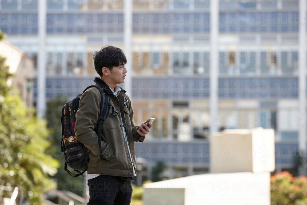 Young Asian university student using mobile phone on-campus - Australian Stock Image