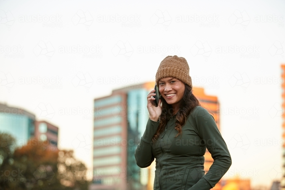 Young Asian woman having fun talking on mobile phone in city - Australian Stock Image