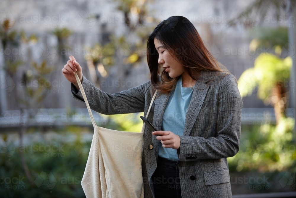 Young Asian woman holding shopping bag outdoors at enclave - Australian Stock Image