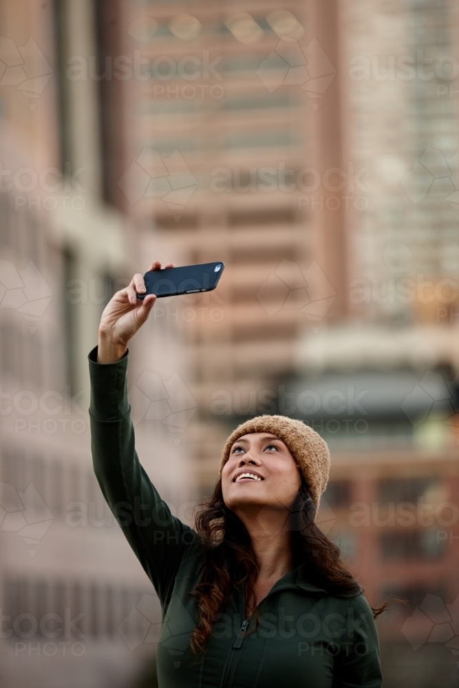 Young Asian woman taking a selfie with mobile phone in city - Australian Stock Image