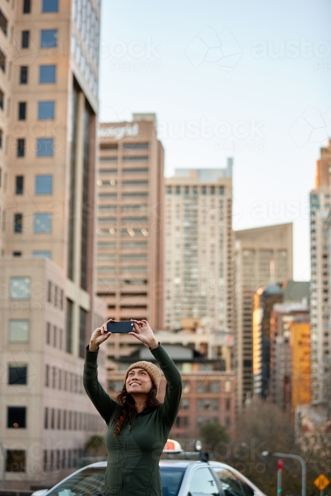 Young Asian woman taking a selfie with mobile phone in city - Australian Stock Image
