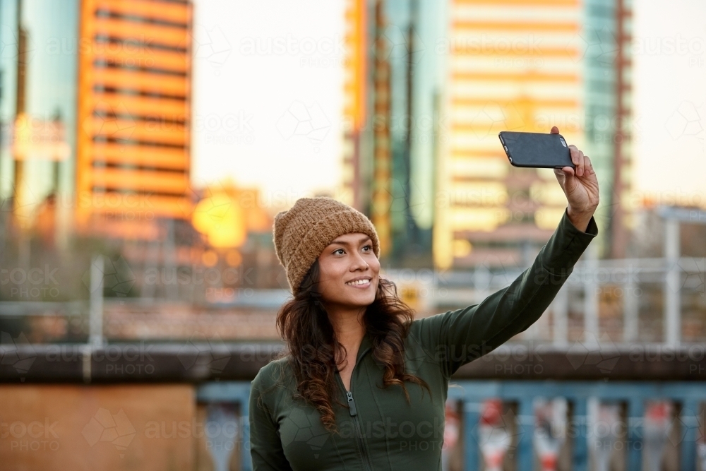 Young Asian woman taking a selfie with mobile phone in city - Australian Stock Image