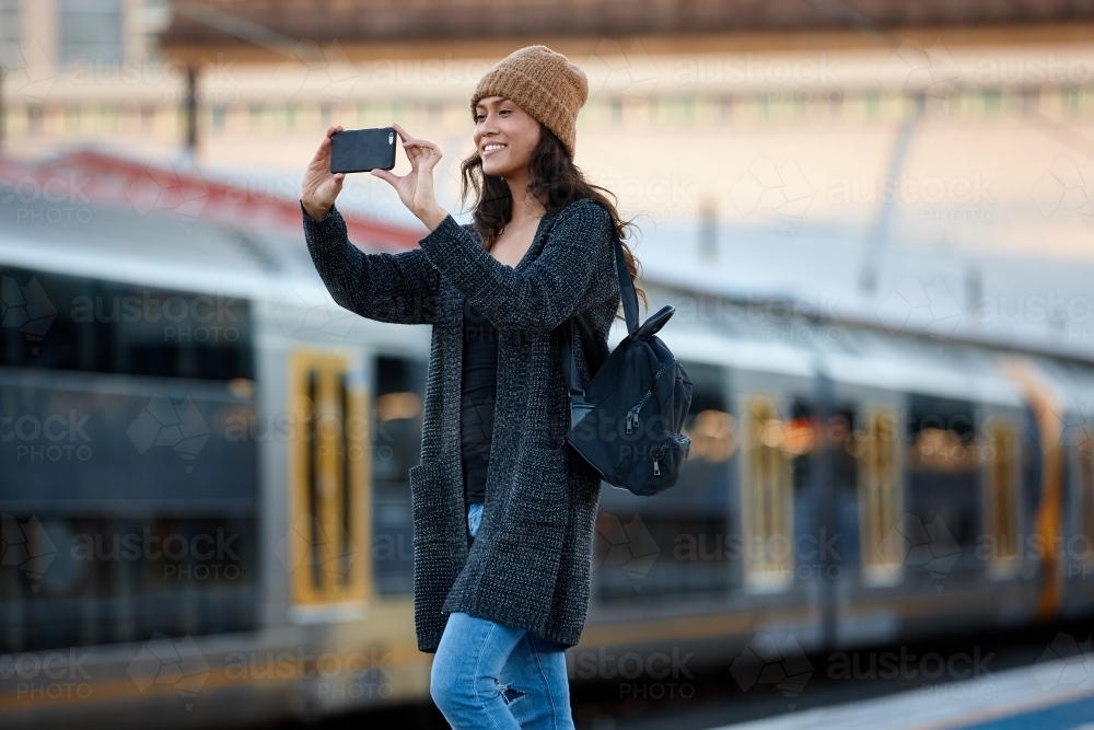 Young Asian woman taking photo with mobile at train station - Australian Stock Image