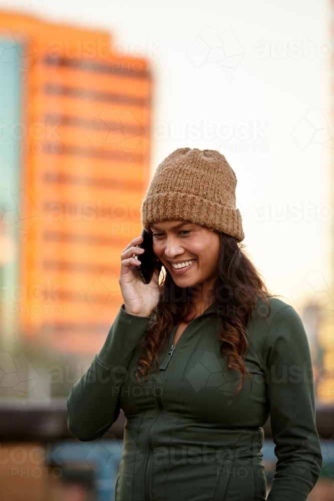 Young Asian woman talking on mobile phone in city - Australian Stock Image