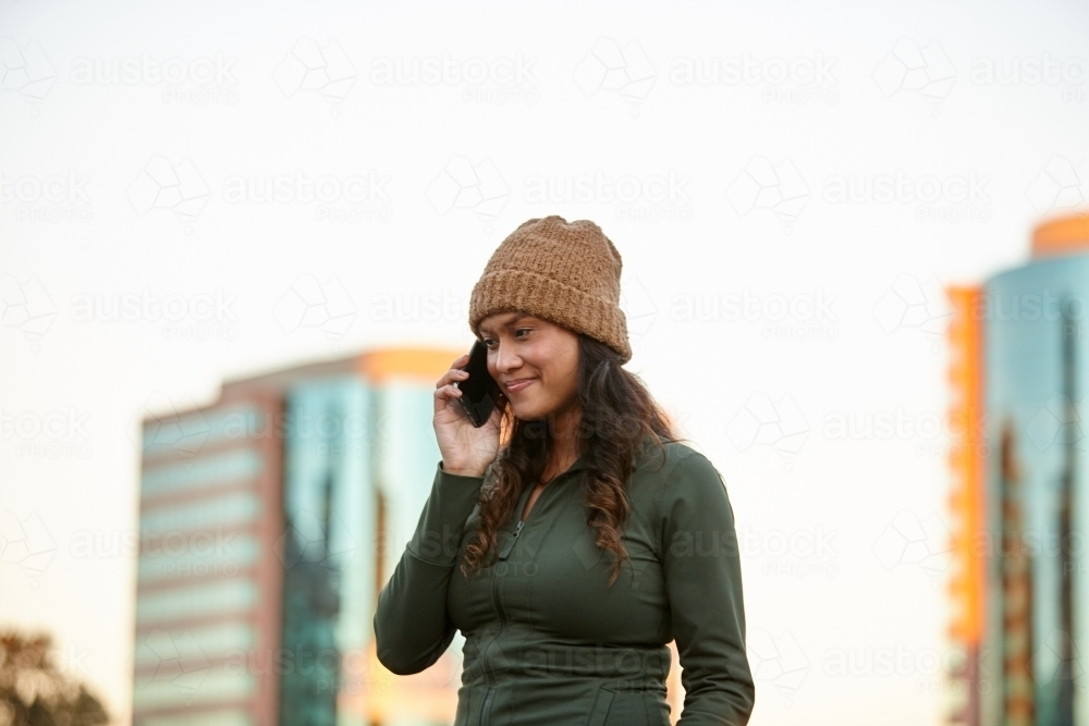 Young Asian woman talking on mobile phone in city - Australian Stock Image