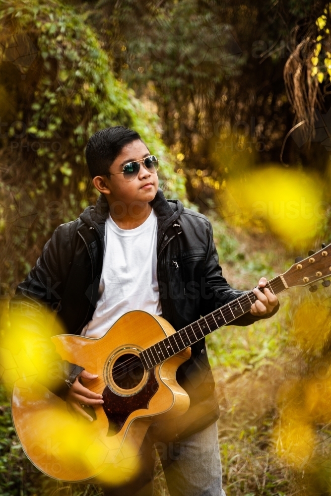 Young aussie boy wearing sunnies and playing guitar - Australian Stock Image
