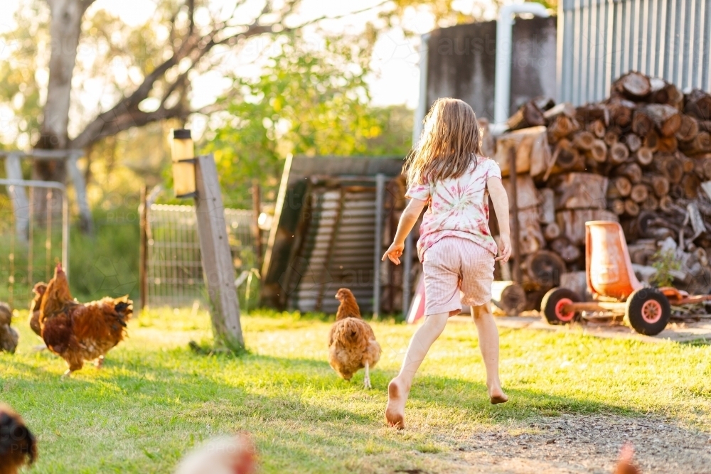 Young Aussie child chasing chickens on Australian farm - Australian Stock Image