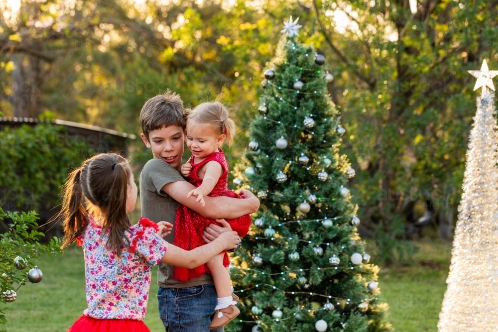 Young Aussie cousins hug in greeting outside at Christmas family gathering - Australian Stock Image