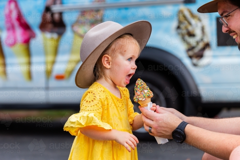 Young Aussie girl at local event eating ice-cream with sprinkles on Australia Day - Australian Stock Image