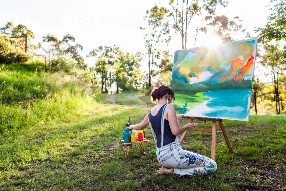 Young aussie person working on landscape painting in nature outdoors - Australian Stock Image