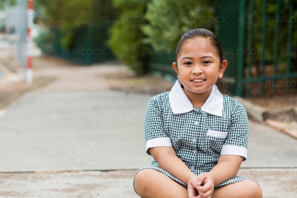 Image of Young Aussie school kid sitting outside school - Austockphoto