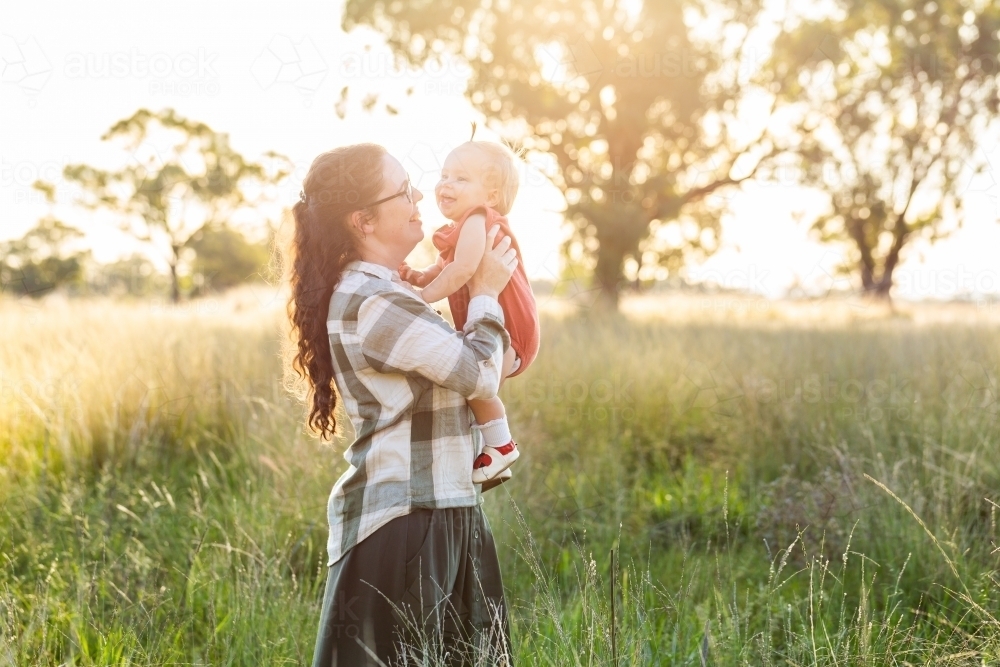 Young australian country woman with baby outside in warm sunlight on farm - Australian Stock Image