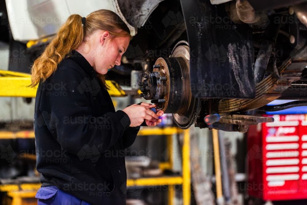 Workcomp Mechanic Image of young australian mechanic working on wheels of vehicle up on ...