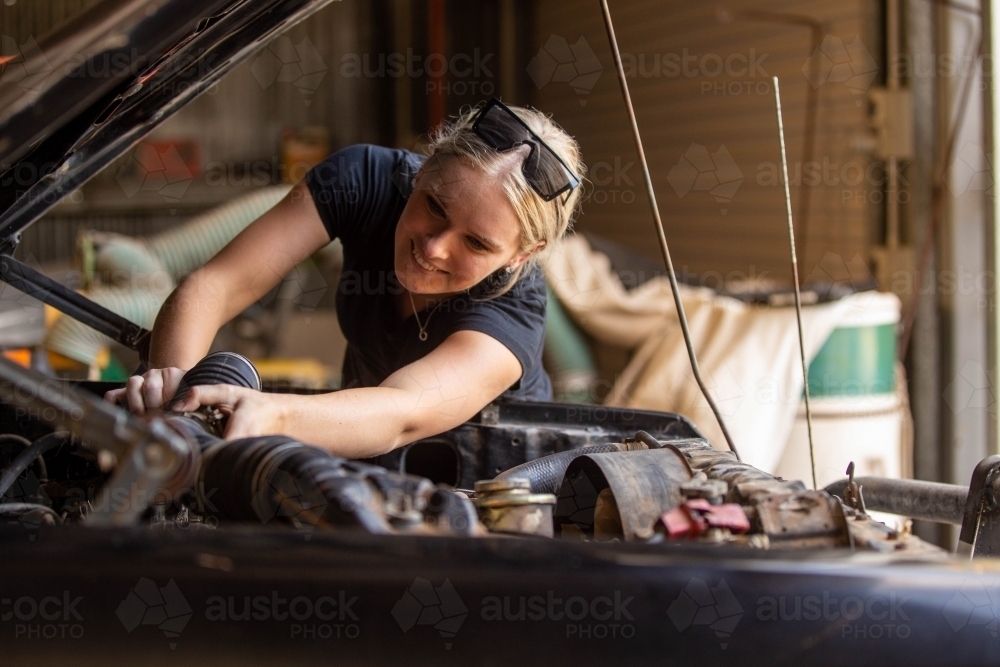 young australian tradesperson mechanic fixing car engine in automotive repair garage - Australian Stock Image