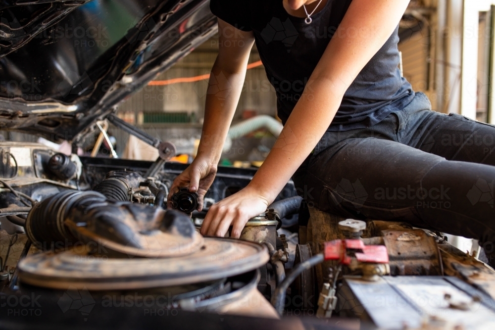 young australian tradesperson mechanic fixing car engine in automotive repair garage - Australian Stock Image