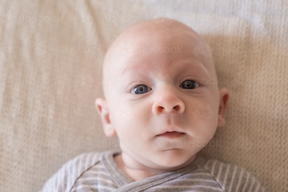 Young baby boy lying on bed - Australian Stock Image