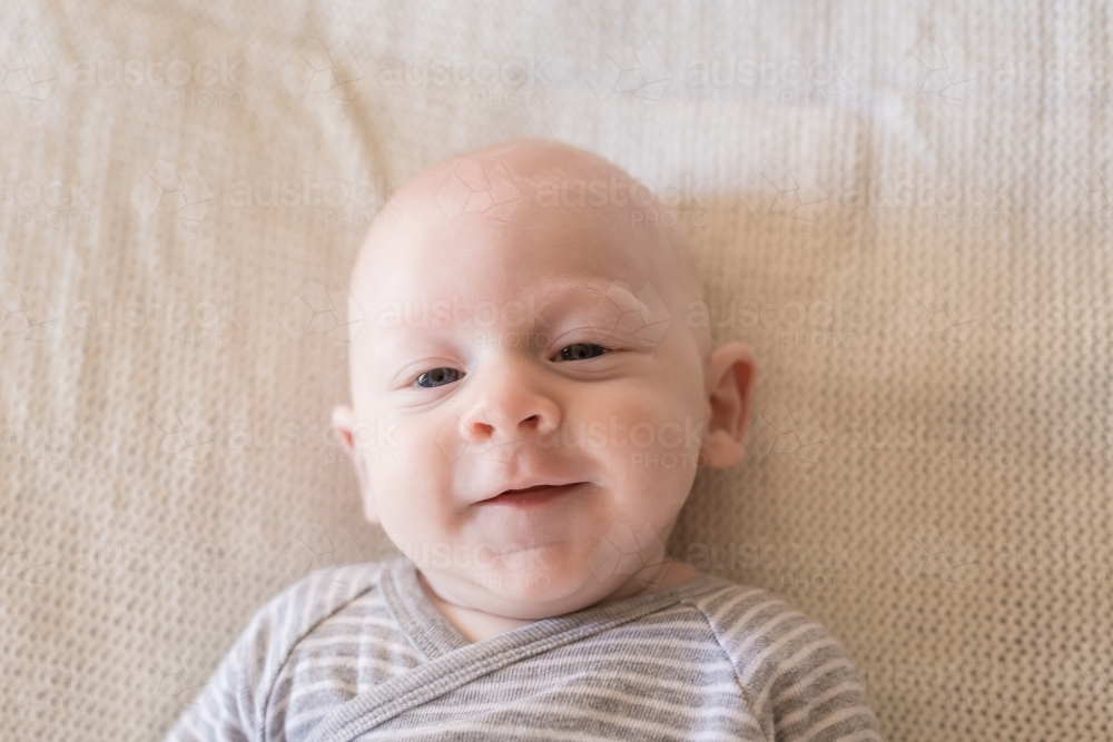 Young baby boy lying on bed - Australian Stock Image