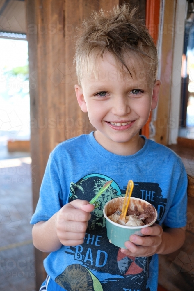 Young blonde boy eating ice cream in a suburban gelateria in Brisbane - Australian Stock Image