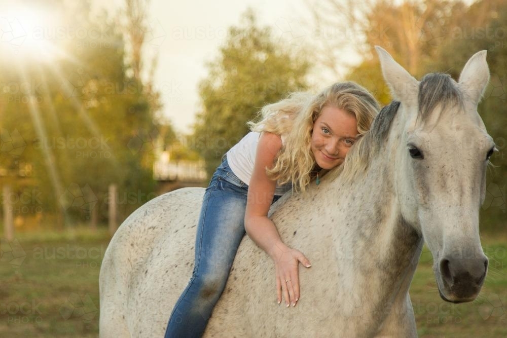 Young blonde girl lying on her horse - Australian Stock Image