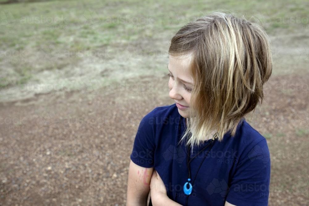 Young blonde girl standing outside looking away - Australian Stock Image