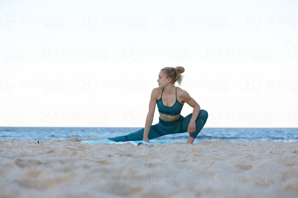 Young blonde-haired woman at beach doing yoga - Australian Stock Image
