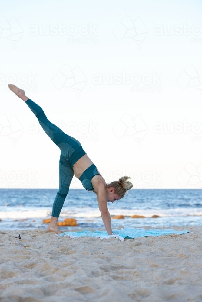 Young blonde-haired woman at beach doing yoga - Australian Stock Image