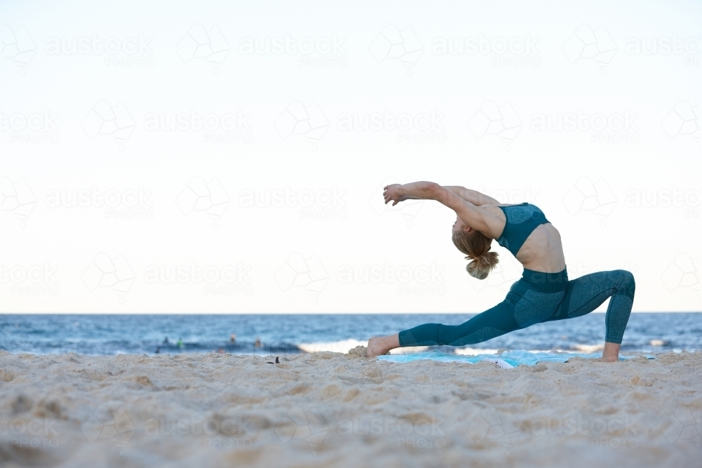 Young blonde-haired woman at beach doing yoga - Australian Stock Image