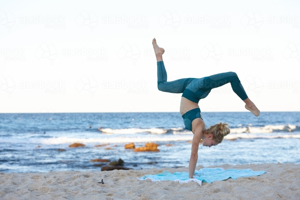 Young blonde-haired woman at beach doing yoga - Australian Stock Image