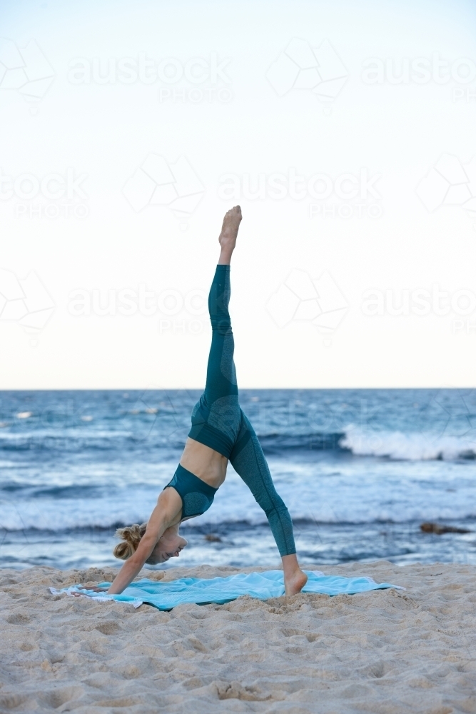 Young blonde-haired woman at beach doing yoga - Australian Stock Image