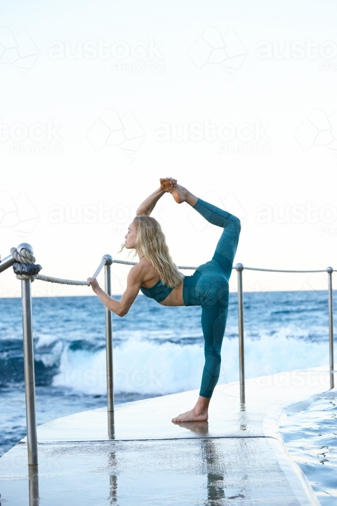 Young blonde-haired woman at beach doing yoga - Australian Stock Image