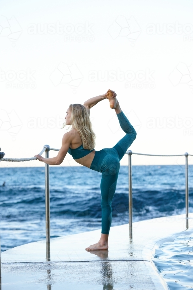 Young blonde-haired woman at beach doing yoga - Australian Stock Image