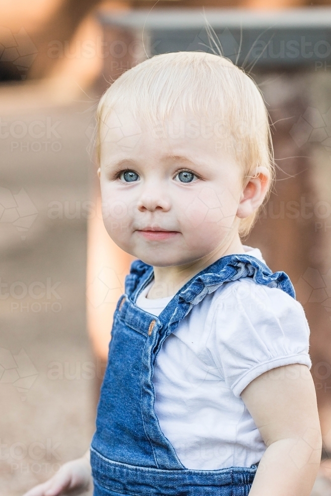 Young blonde toddler girl exploring in garden - Australian Stock Image