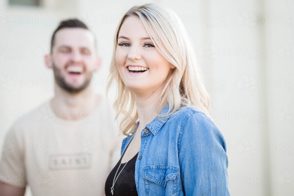 Young blonde woman laughing with boyfriend in background - Australian Stock Image