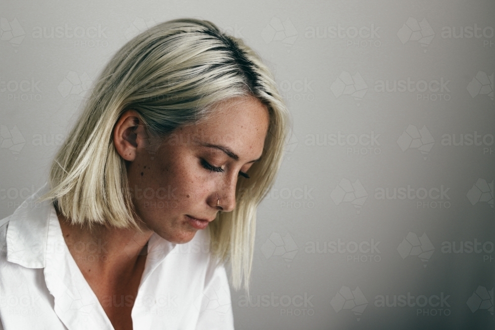 Young blonde woman looking down against a white background - Australian Stock Image