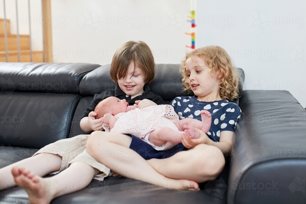 Young boy and girl holding an infant - Australian Stock Image
