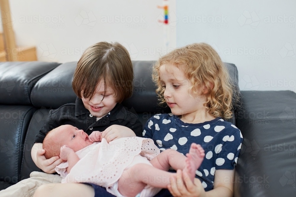Young boy and girl holding baby - Australian Stock Image